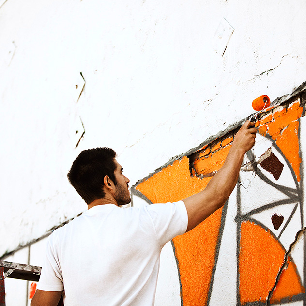 man paints a mural on wall