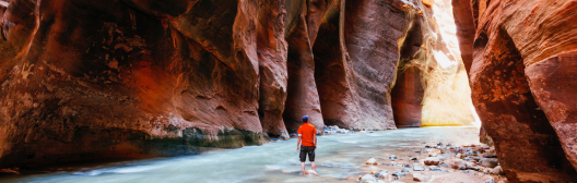 Man standing in between 2 mountains and in a river