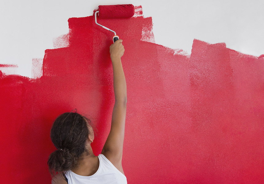 A girl painting red color on wall