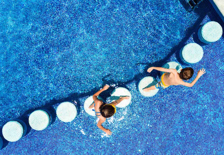 Kinder spielen am Rand eines Pools unter der strahlenden Sonne.