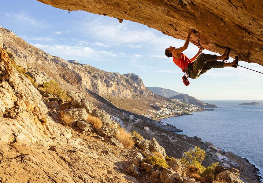 Personne faisant de l'escalade sur une falaise surplombant la mer.