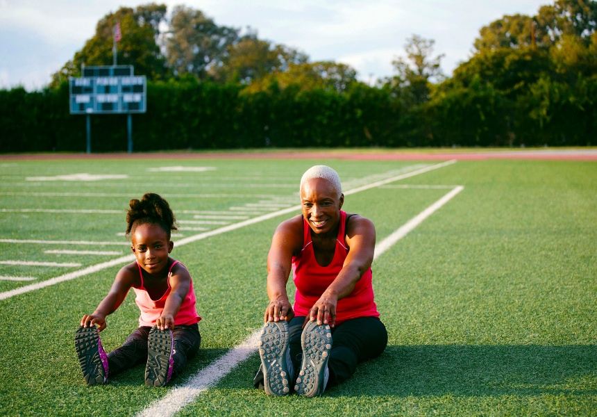 Woman and grandchild stretching on field