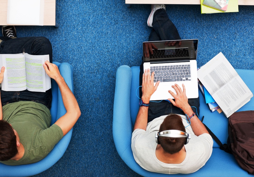 Overhead view of a young man listening to music and browsing on his laptop