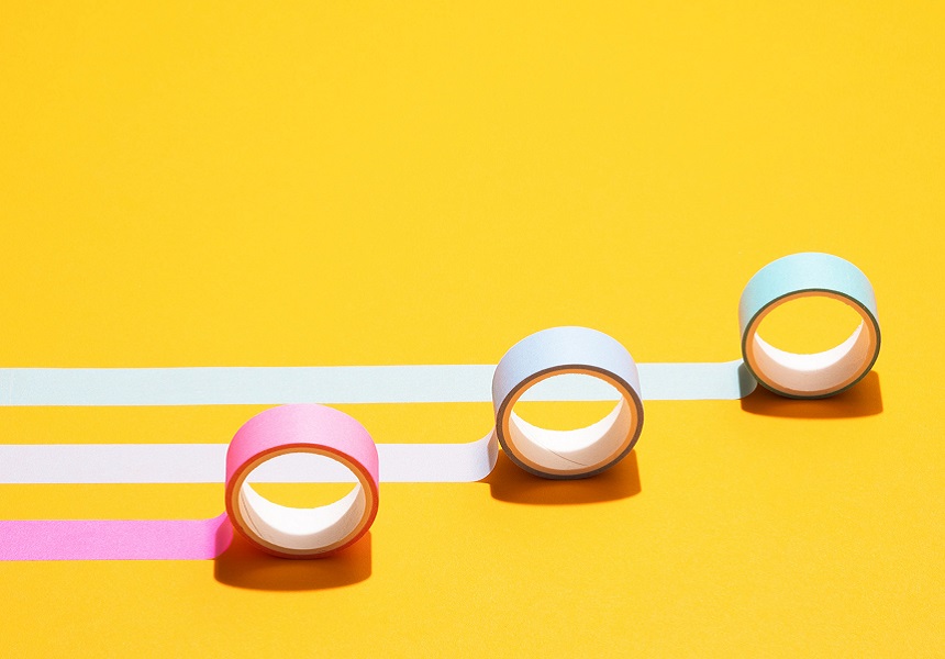 Three rolls of colored tape on a yellow background