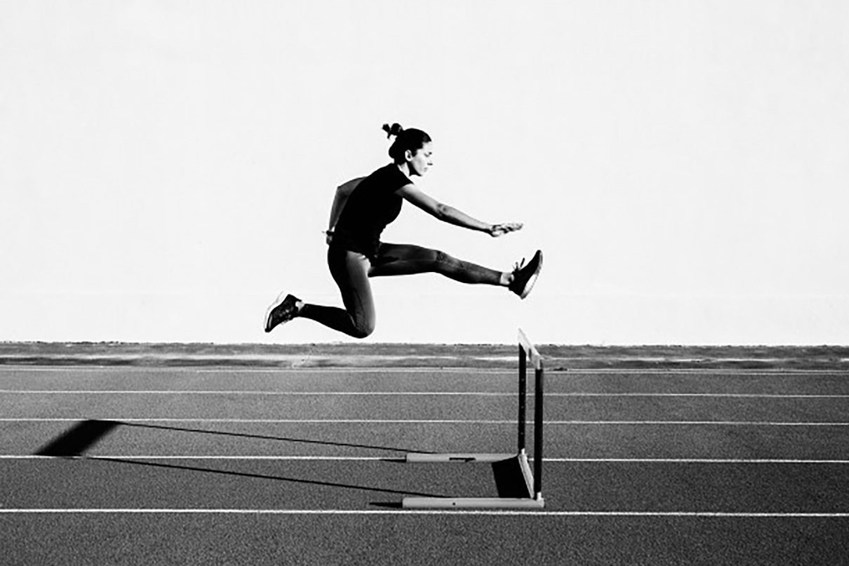 Female athlete leaping over a hurdle