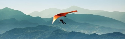 Hang glider soaring above wavy mountain ranges