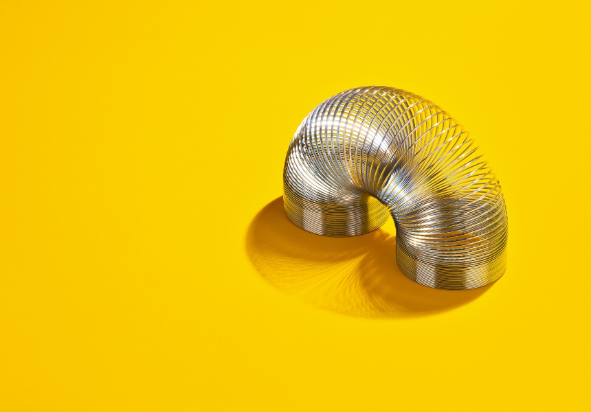 Silver slinky against yellow background