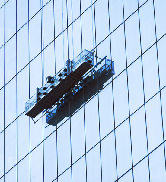 An image of a crane against a tall building with glass windows