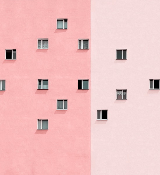 Minimalist building facade with small square windows arranged across pink and light gray walls