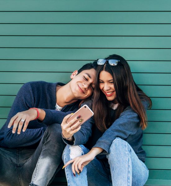 two young people who look like friends smiling and taking a selfie photo