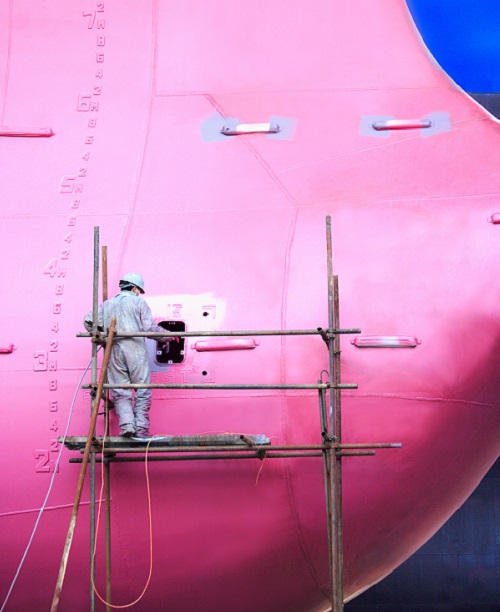 A worker painting a building pink