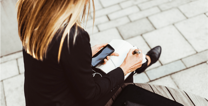 Girl observing phone screen and pen 