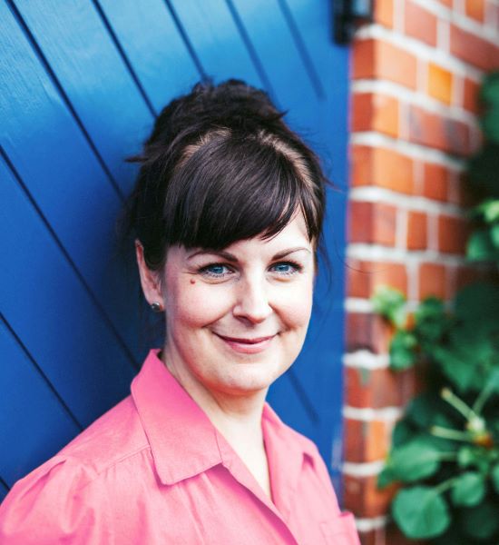 portrati of a middle aged woman smiling wearing a pink button down shirt