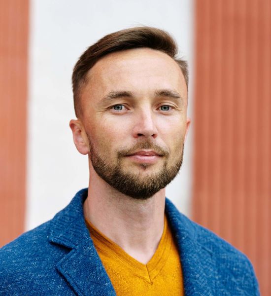 portrait of a young man wearing an orange shirt and blue jacket