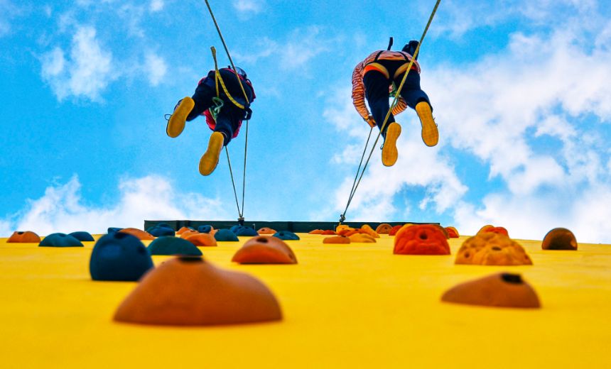 Two people climbing rock wall