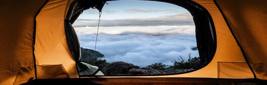 View from inside a yellow tent looking out at a rocky landscape and cloudy sky