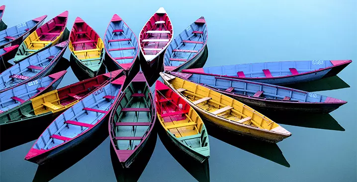 Bunte Boote aus Holz liegen in einem Kreis angeordnet