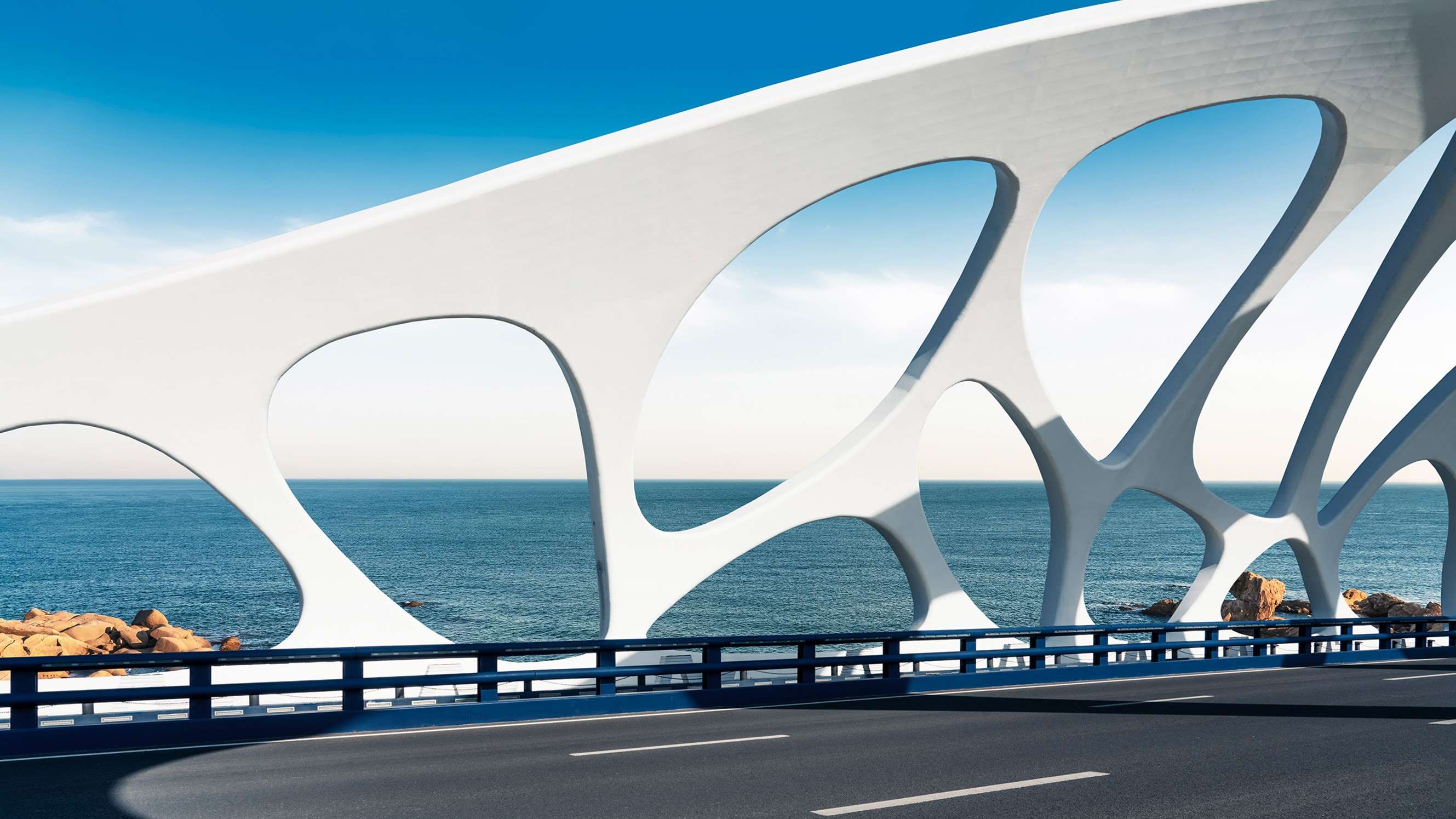 Moderne brug met witte bogen over de zee.