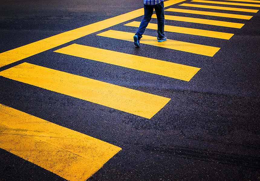 man walking across yellow cross walk.